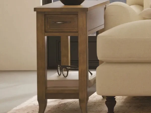 Wooden side table with drawer beside a sofa.