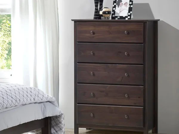 Dark wood dresser with five drawers in bedroom.