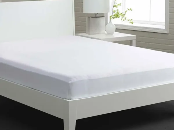 White bed with fitted sheet and nightstand.
