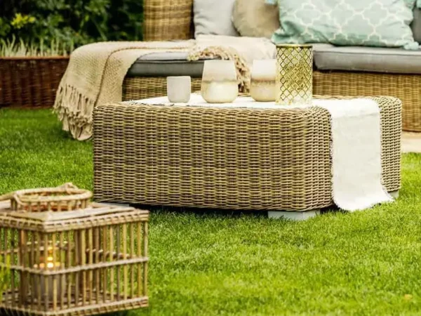 Outdoor wicker furniture with candles on grass.