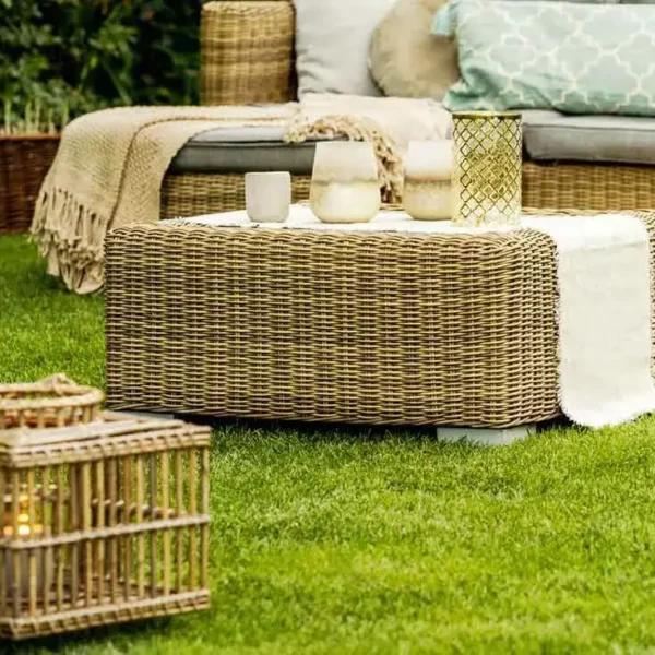 Outdoor wicker furniture with candles on grass.