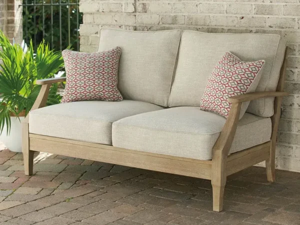 Outdoor wooden loveseat with cushions and pillows.