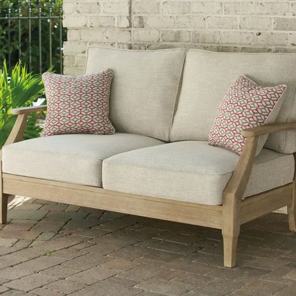 Outdoor wooden loveseat with cushions and pillows.