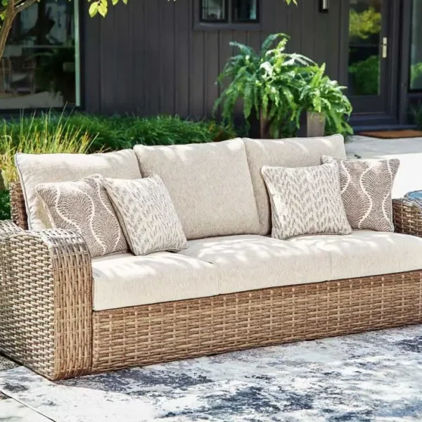 Outdoor wicker sofa with beige cushions and pillows.