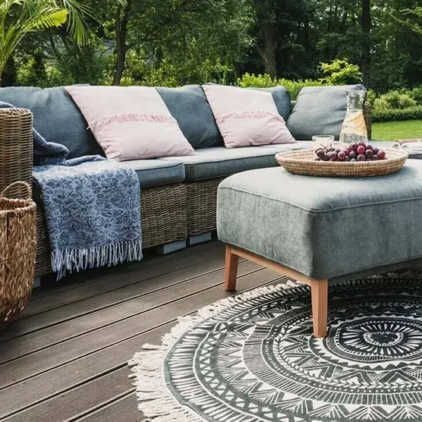 Outdoor patio with sofa, ottoman, and decorative rug.