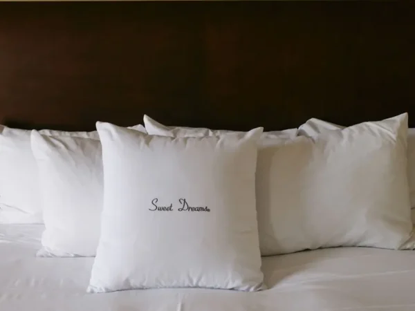 White pillows on bed, one says 'Sweet Dreams'.