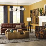 Living room with leather sofa, mustard walls, and modern lighting.