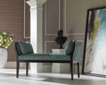 Teal upholstered wooden bench in a classical interior setting.