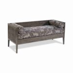 Grey wooden daybed with floral pattern cushions and bolster pillows.