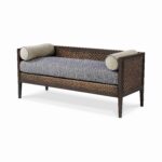 A dark wood daybed with patterned cushions and bolsters.