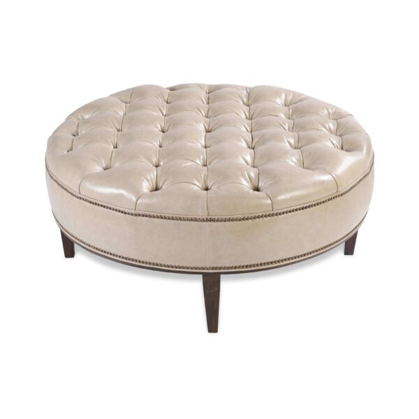 Large circular button-tufted ottoman in light beige leather.