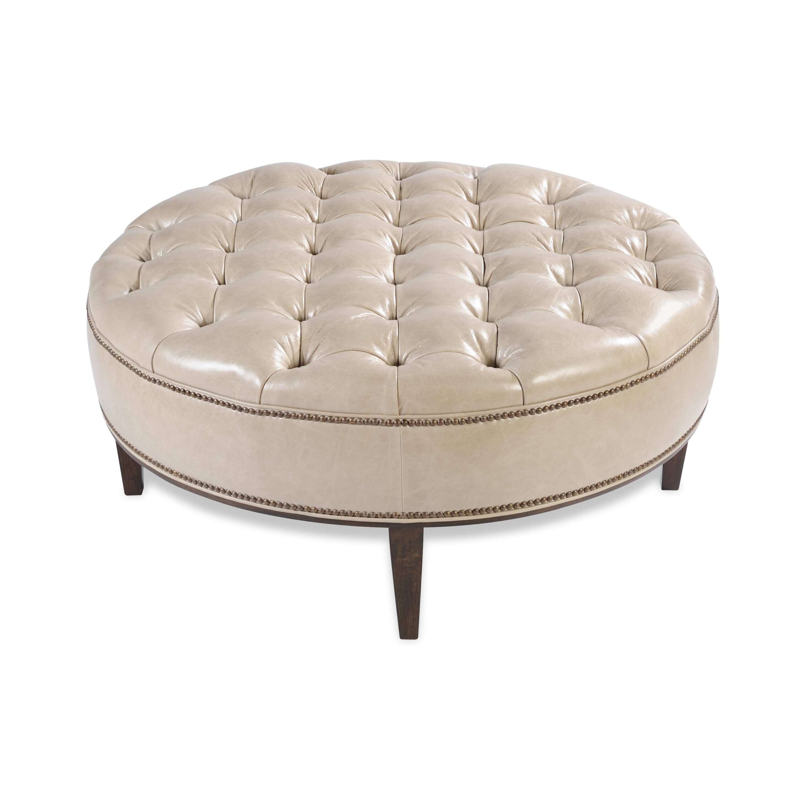 taylor made round ottoman Large circular button-tufted ottoman in light beige leather.