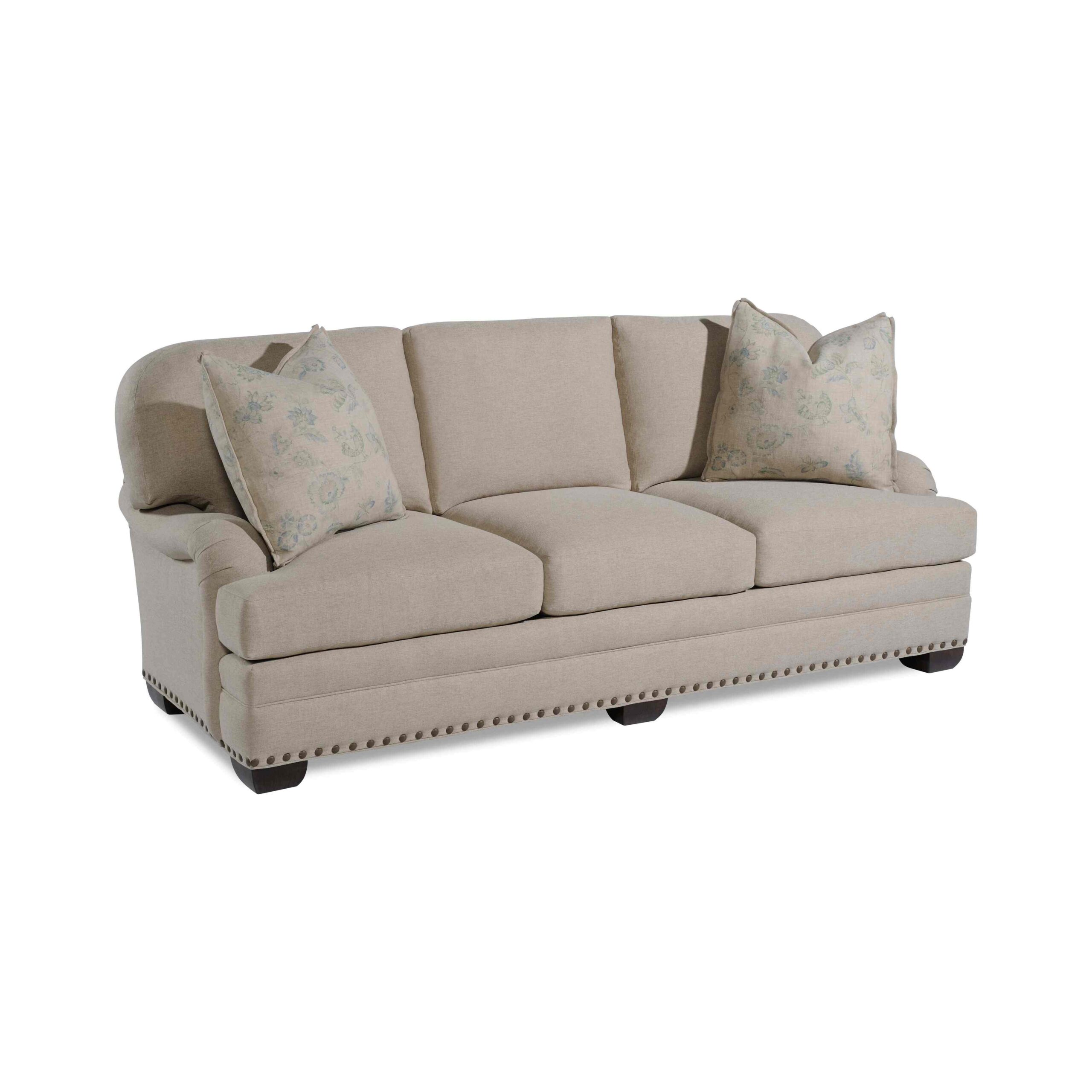 taylor made standard sofa Beige three-seater sofa with floral pillows and nailhead trim.