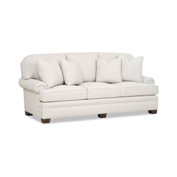 Traditional cream three-seater sofa with rolled arms and pillows.